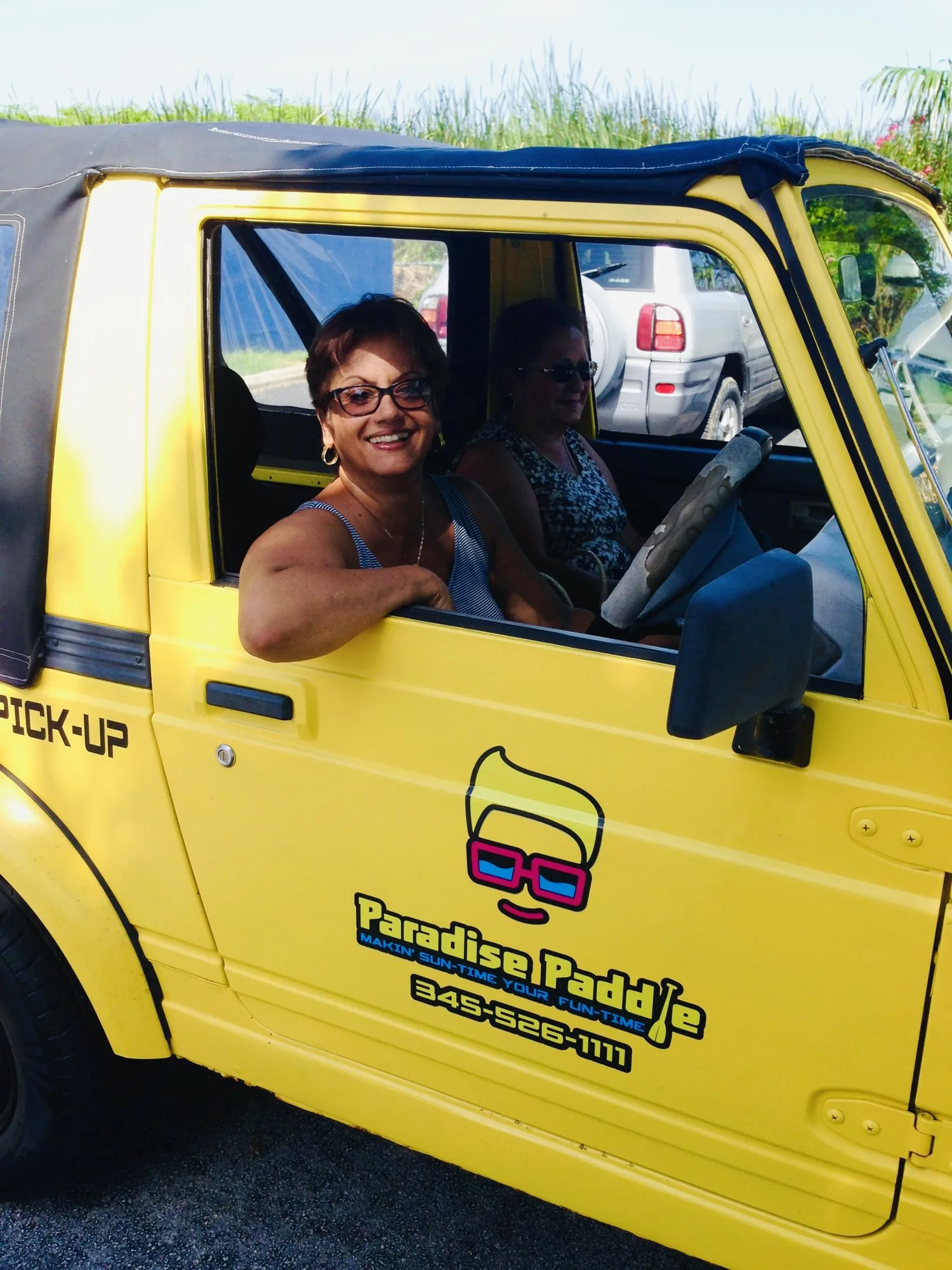Guests smiling from the yellow Paradise Paddle pick-up truck