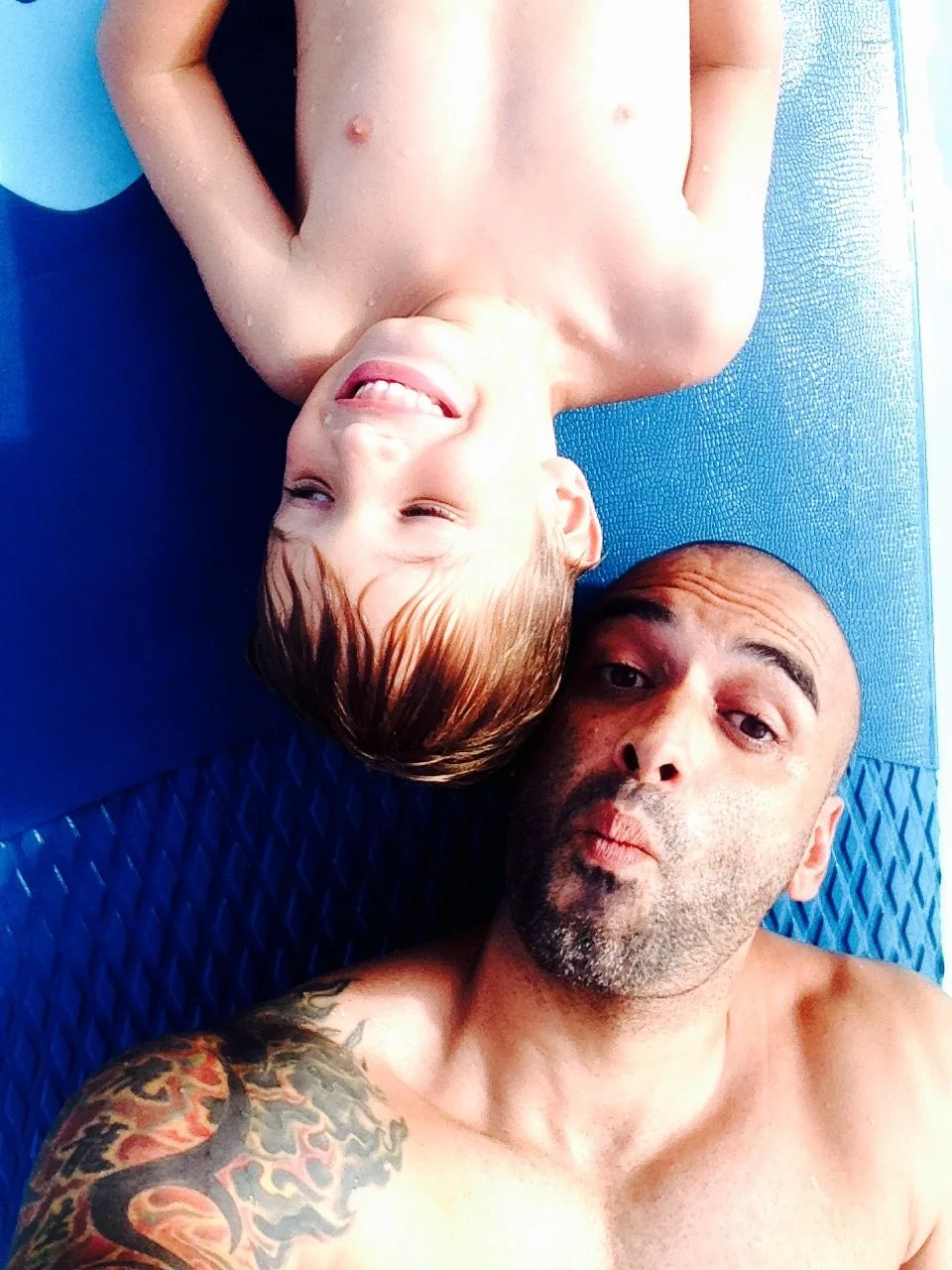 Man and young boy taking a selfie while lying on a paddleboard