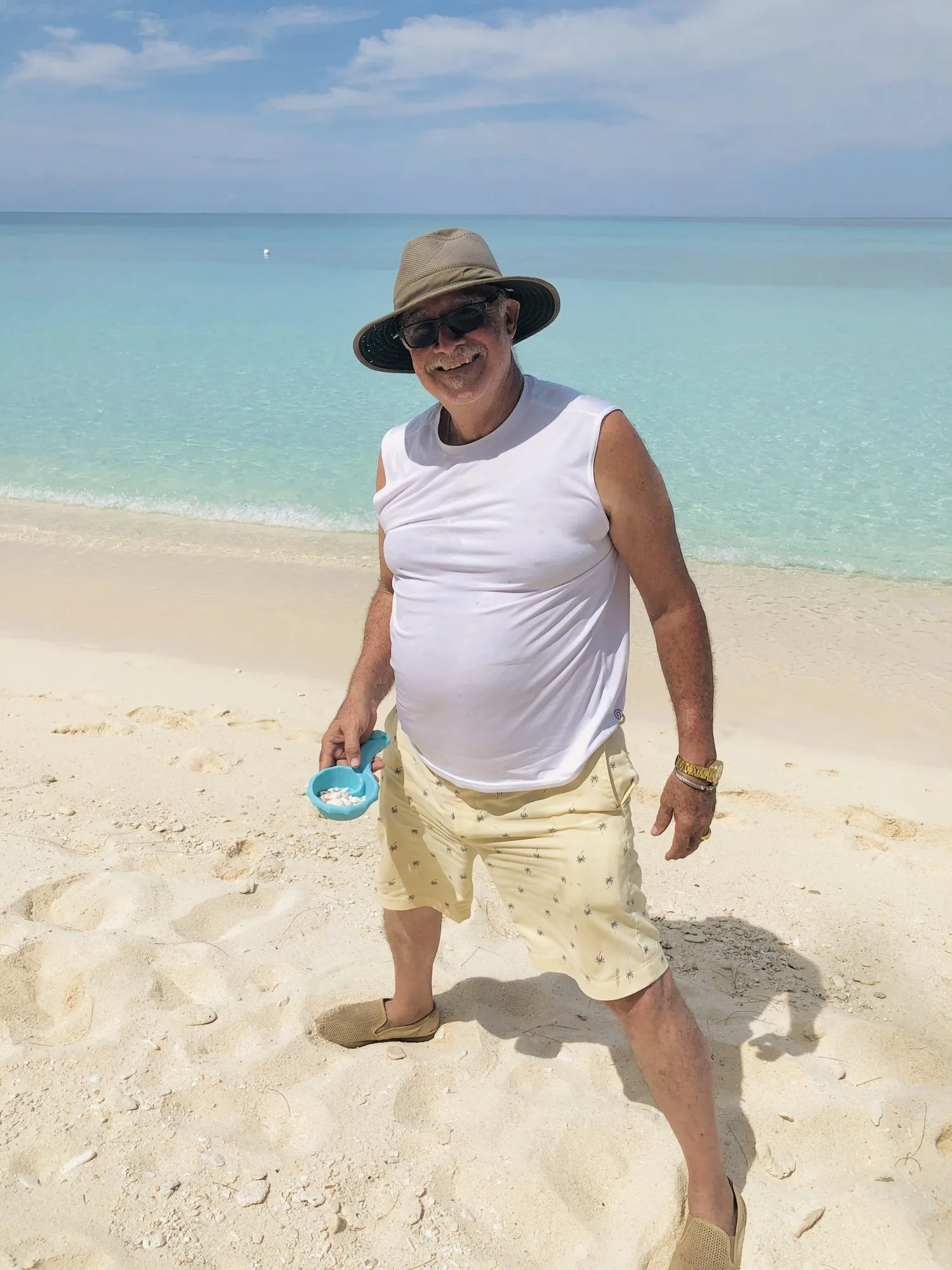Smiling man in a sun hat on the white sand of Seven Mile Beach